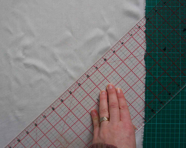 cream fabric on a green background with a clear ruler marking out the 45 degrees