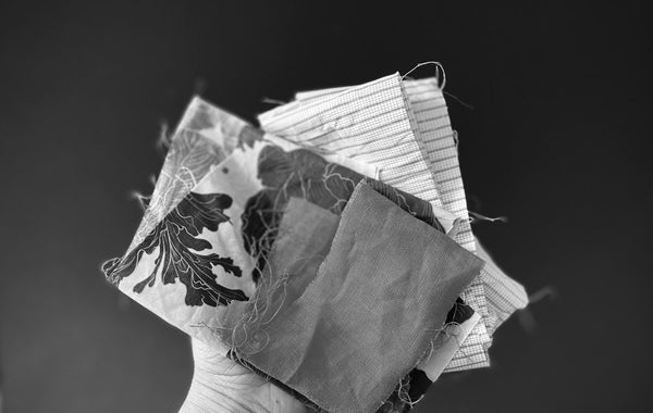 a black and white image of fabrics being held in a hand