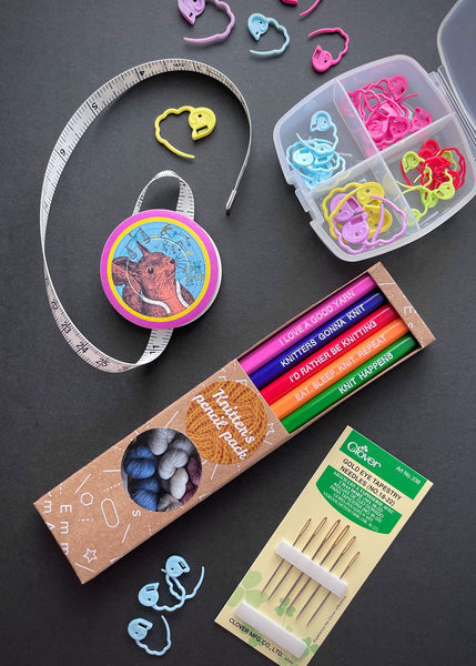 a collection of brightly coloured pencils, tape measure, and stitch markers for knitters
