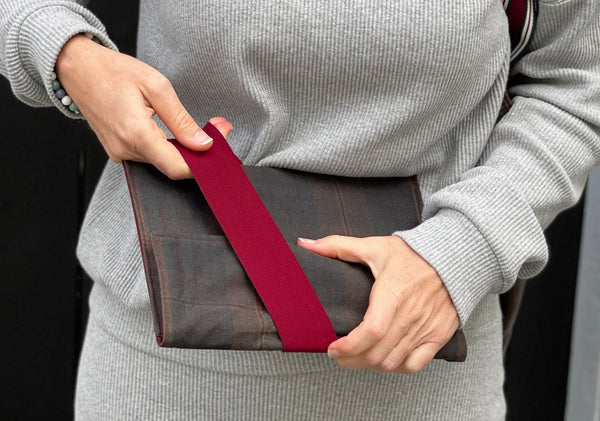 a white woman in a grey outfit is pulling the strap on the oilskin cover.