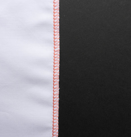 a white piece of fabric to the right hand side with orange overlock stitching on the right hand edge with a black background