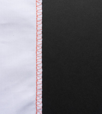 a white pice of fabric to the right hand side with orange sewing machine overlock stitching on the right hand edge with a black background