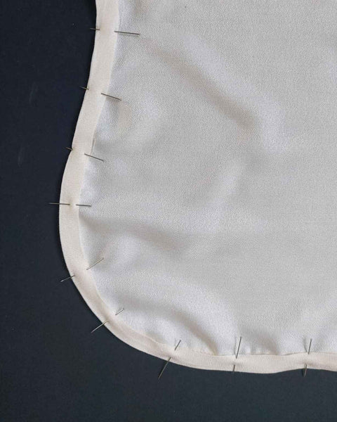 a photo of pins pinned around the curve of a white piece of fabric