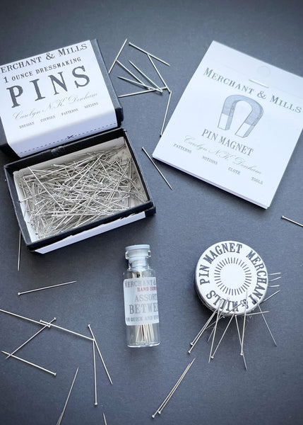 a selection of pins, magnet and needles on a black background