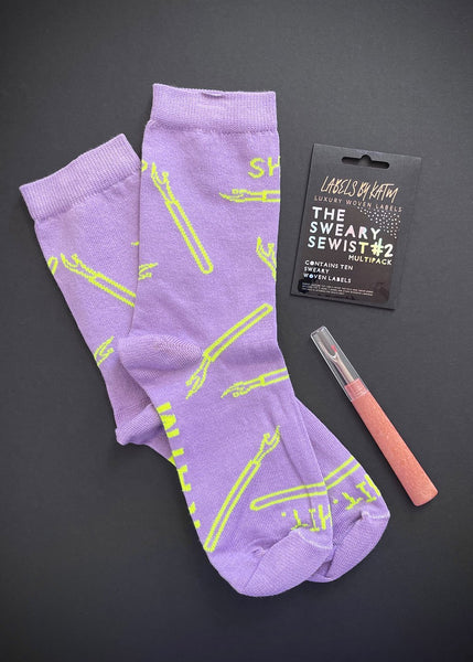 A pair of purple socks, seam ripper and sweary sewist labels