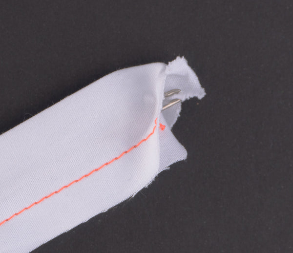 a close up of a loop tuner hook through white fabric on a black background