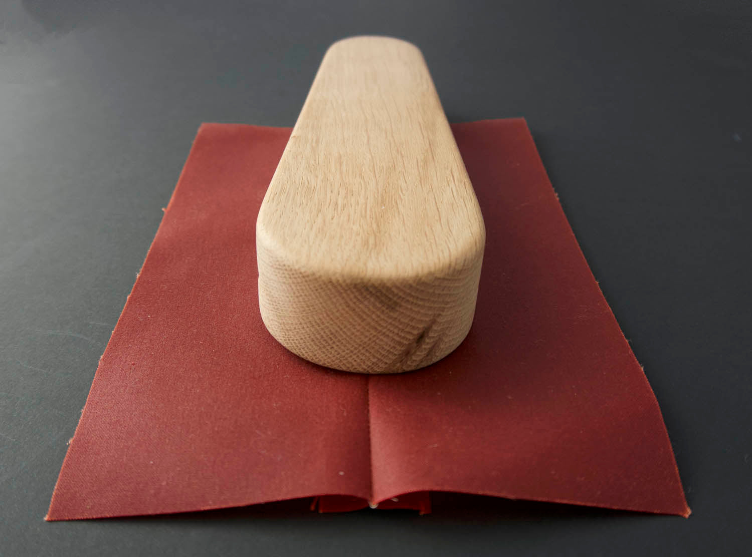 a wooden clapper sat on top of traditional oilskin to press open the seam