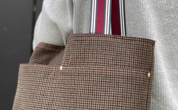 a close up of the where the handles of the bag meets the bag and shows the gold rivets installed at the pocket seams
