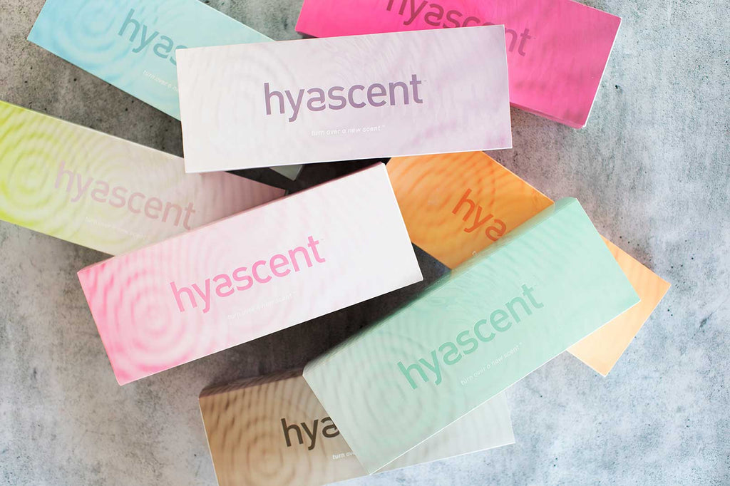 Overhead flatlay image of brightly colored, multicolor long rectangular boxes that each have a ripple effect gradient background illustration and the logo "hysacent" across the center.