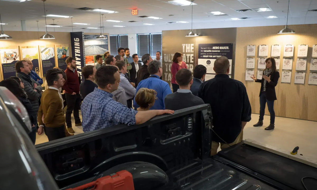 A person speaks to a crowd in an exhibit designed by IDEO for Ford Motor Company to explore possibilities for redesigning the Ford F150 truck. 