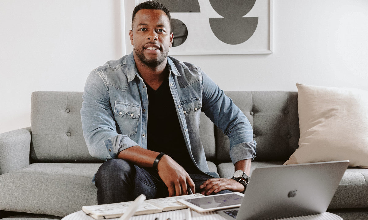 Donald Burlock, Jr. sitting on a couch with a laptop.