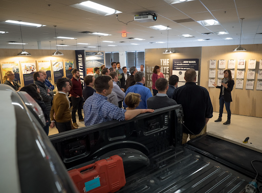 A person speaks to a crowd in an exhibit designed by IDEO for Ford Motor Company to explore possibilities for redesigning the Ford F150 truck. 