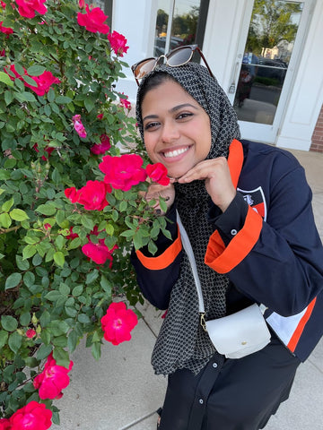 Nusrat smiling with pink flowers.