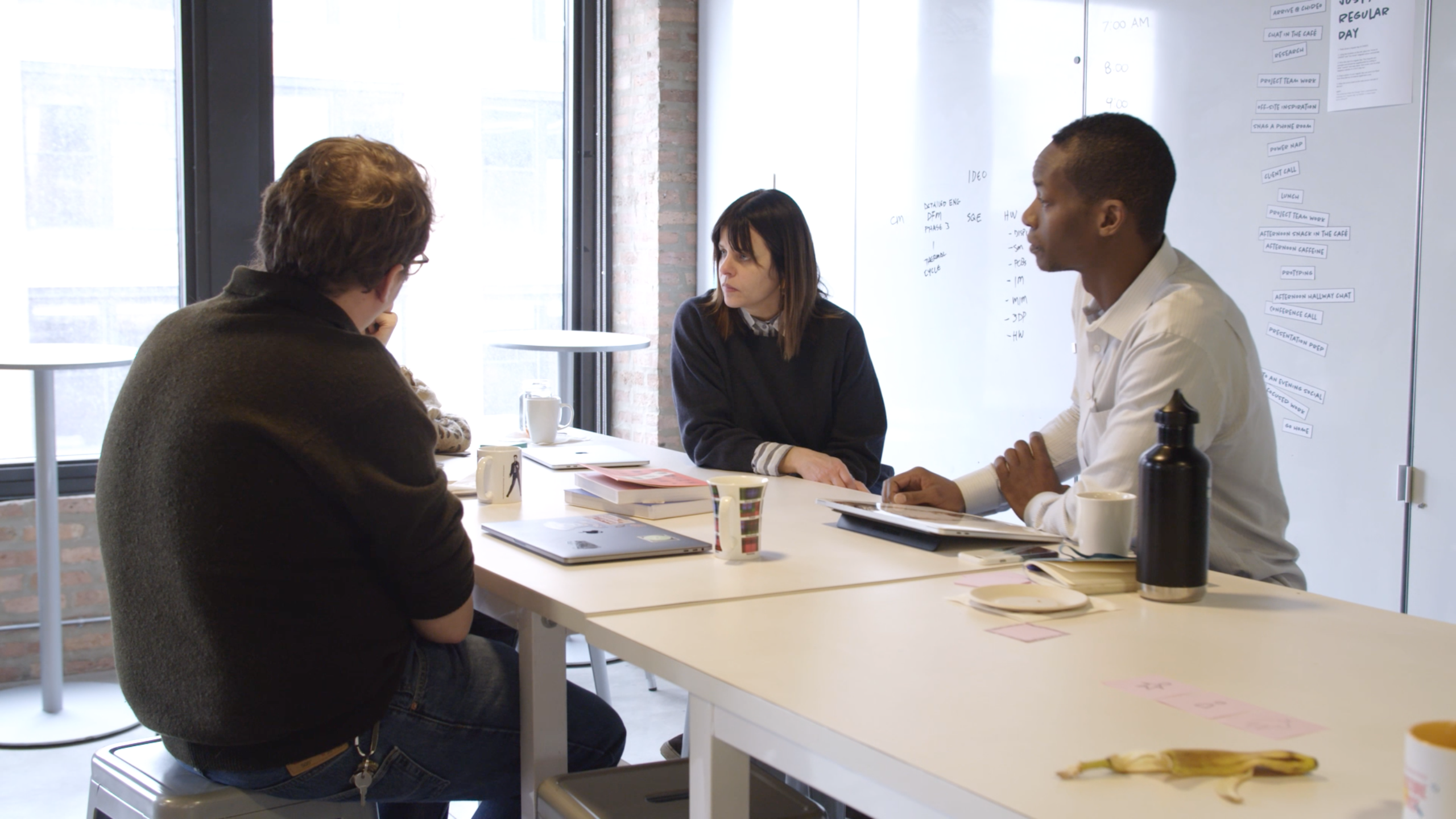 Three people sitting around a table at a meeting.