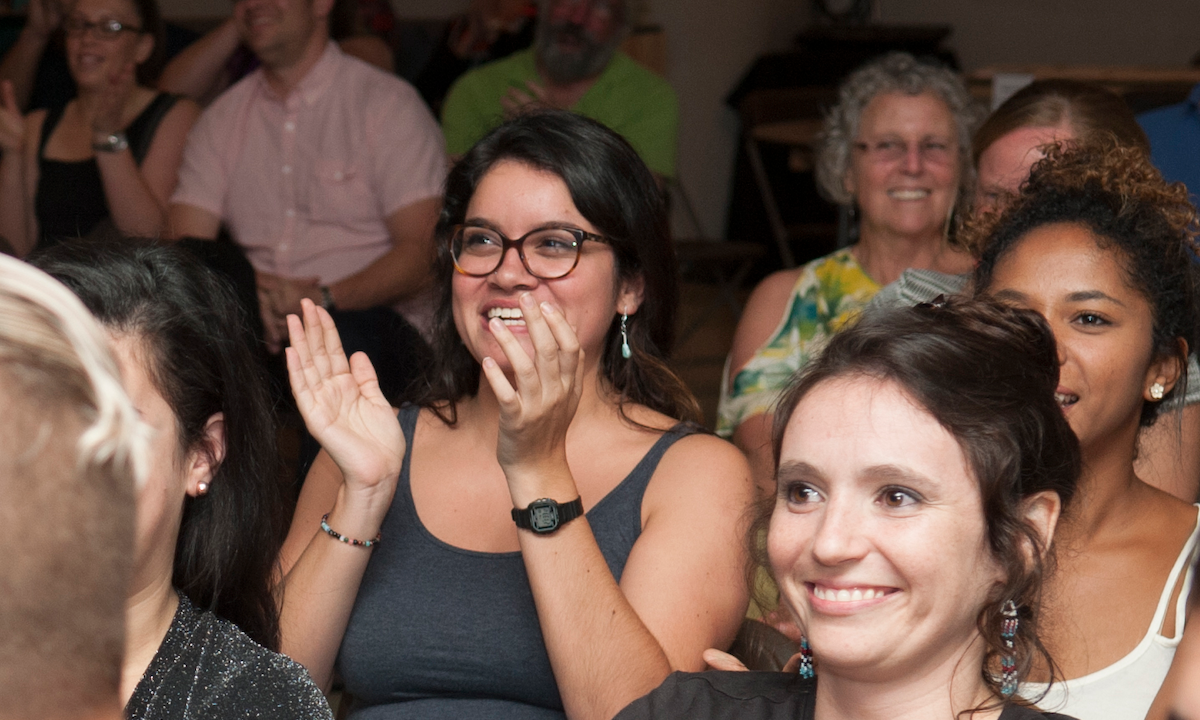 An audience of ten people smiling and clapping.