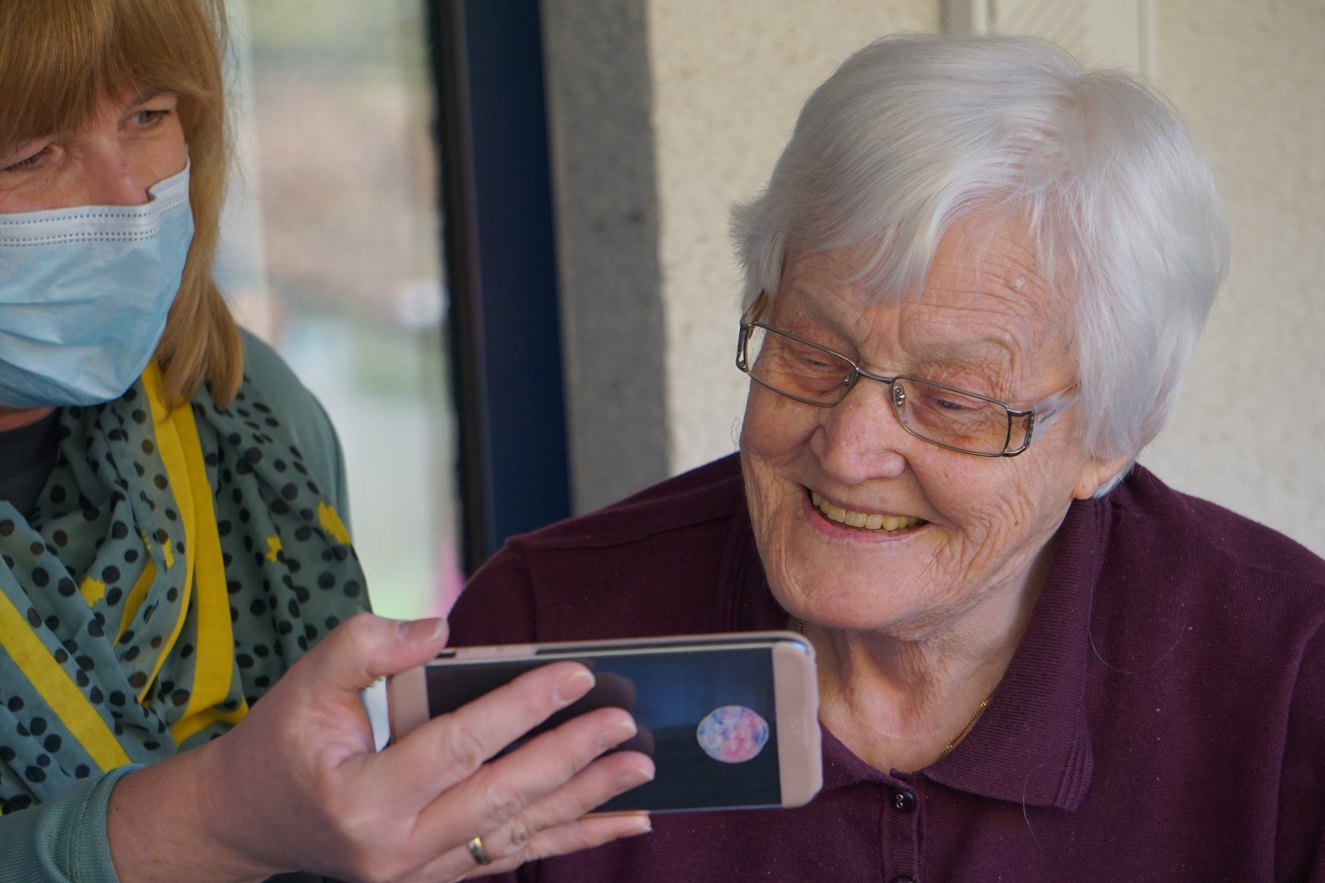 A woman holding a phone for an older adult.