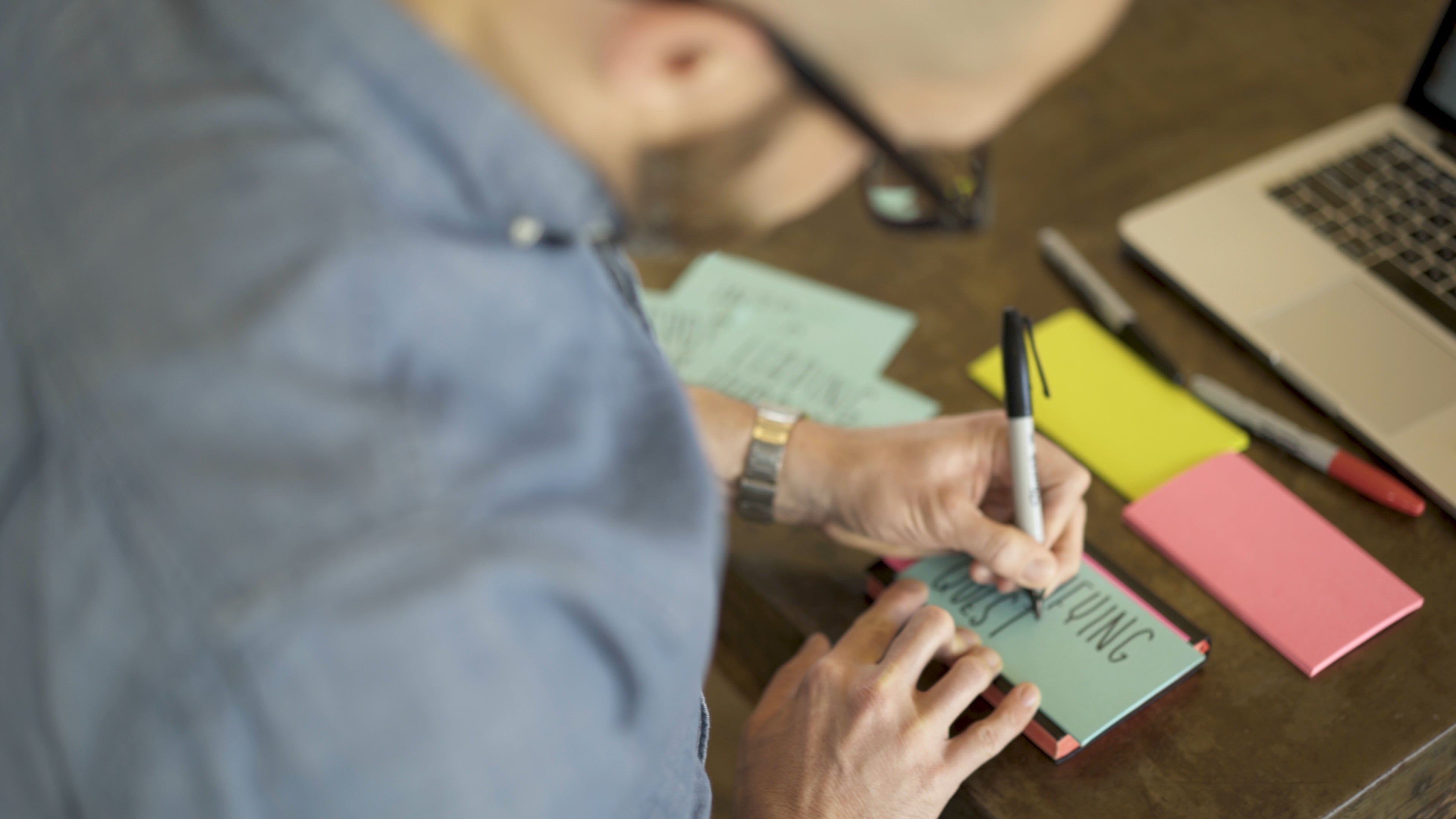 A person writing on a post-it note with a Sharpie.