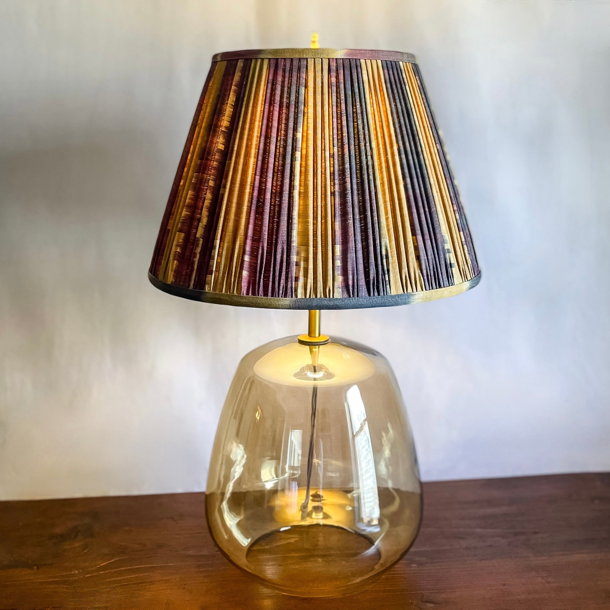 Firat Aubergine Hand Shirred Ikat Lampshade with light on.