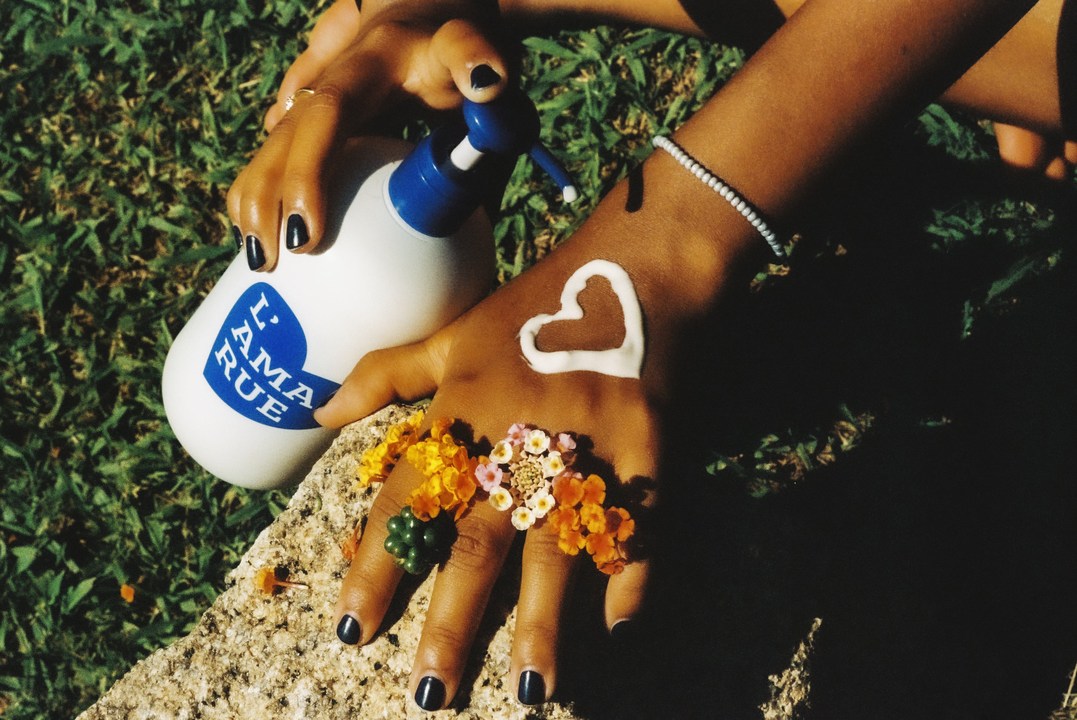 Two hands with flower decorations and sunscreen cream shaped as a heart on one hand.