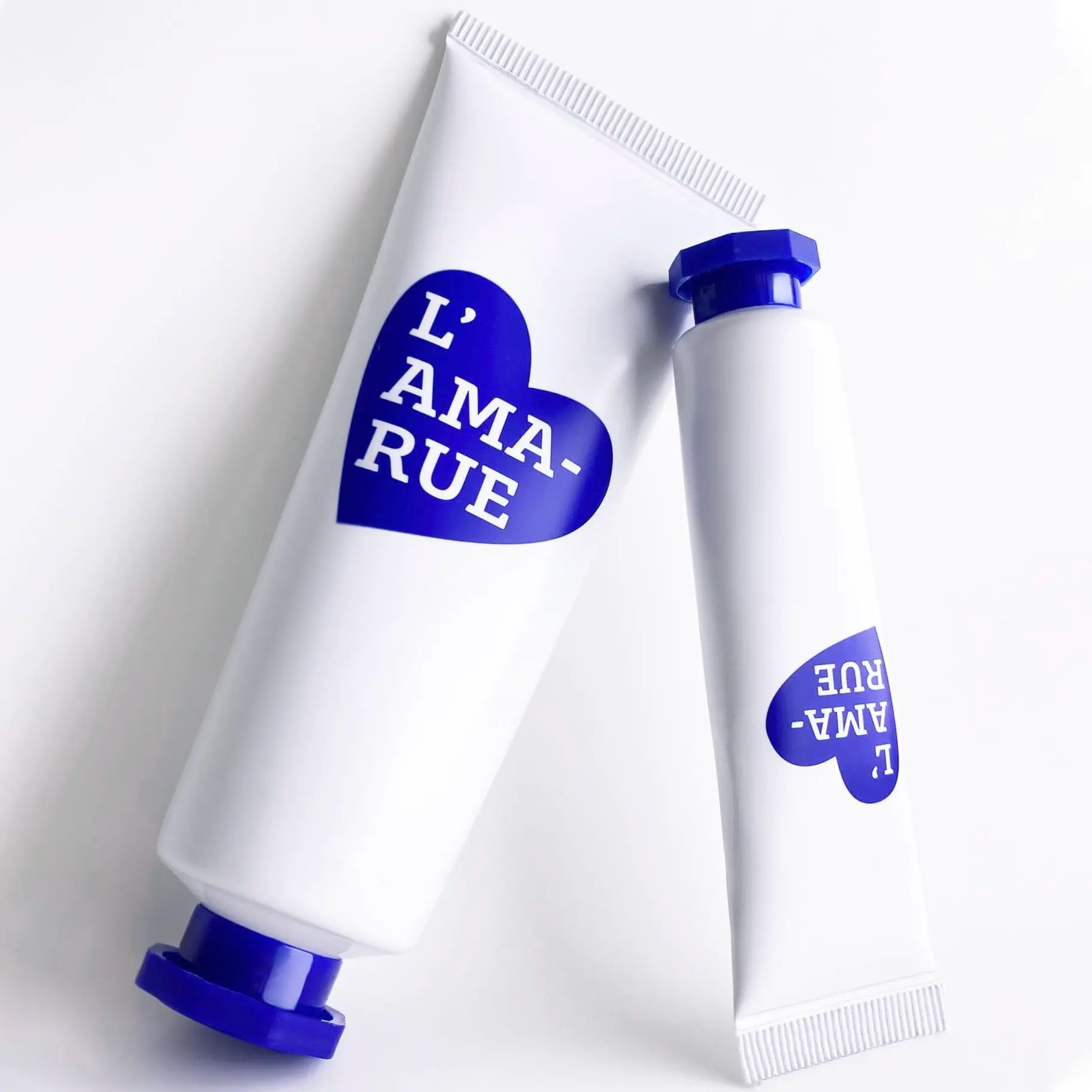 Two white cosmetic tubes with blue branding and caps on a white background.