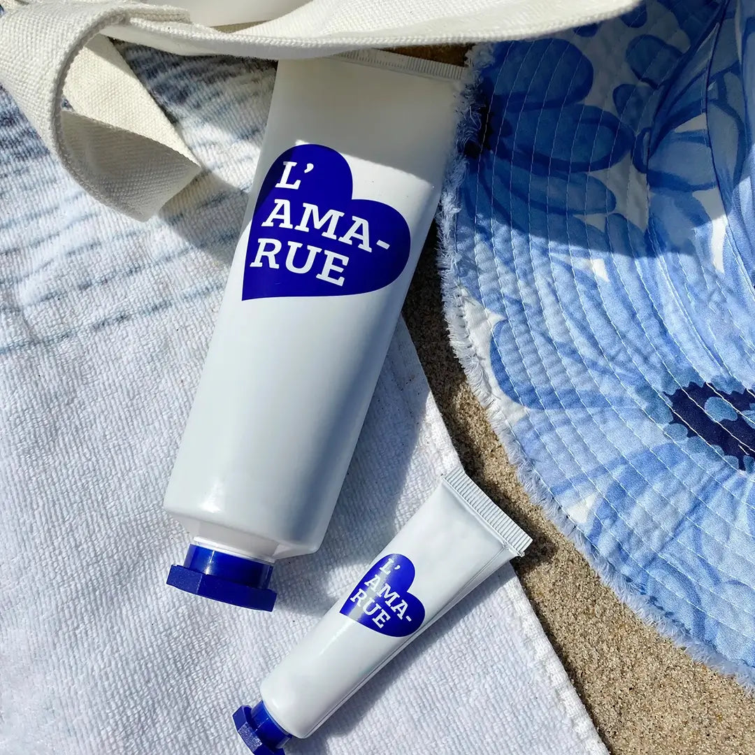 Sunscreen tubes on a towel with a beach tote.