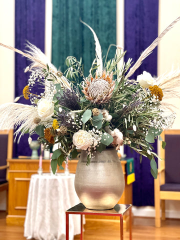 Muted color, dried flower ceremony display in front of church altar