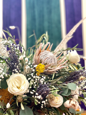 Close-up of dried flower arrangement in front of purple and blue wall