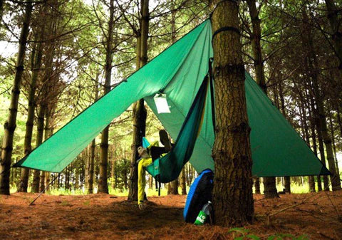 A person laying under the AquaQuest guide tarp in forester green.