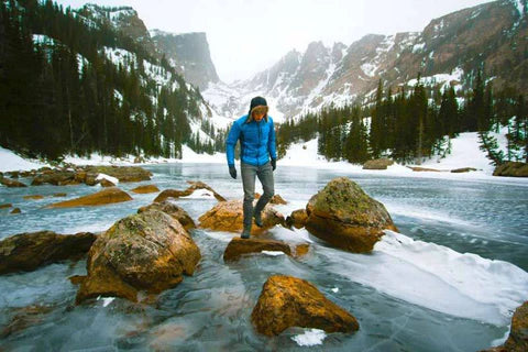A person walking on rocks on a frozen lake.