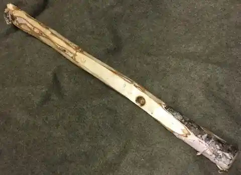 A carved stick with a hole burnt into it.