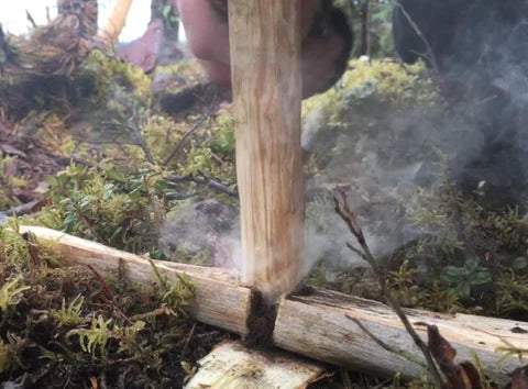 A bushcrafter igniting a fire with two carved sticks in close view.