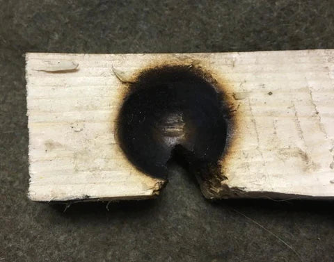 A piece of wood with a hole burnt into it.