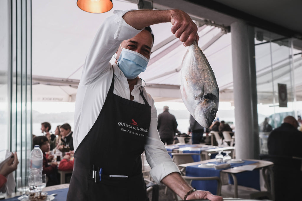 Lison Portugal seafood restaurant waiter holding up a fish 