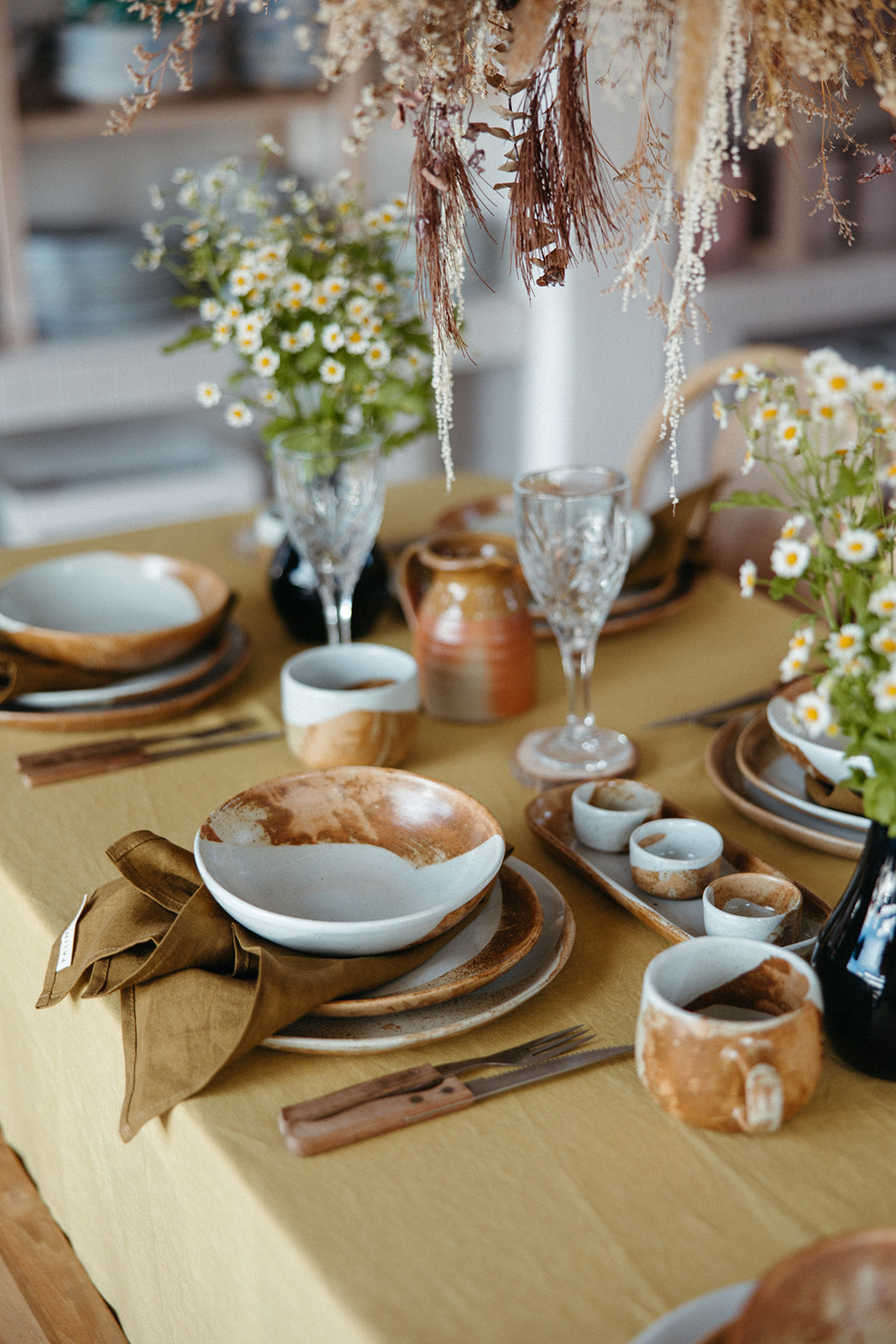 A set table with a yellow Australian Made tablecloth and Soda fired handmade dinner set by Palinopsia Ceramics 