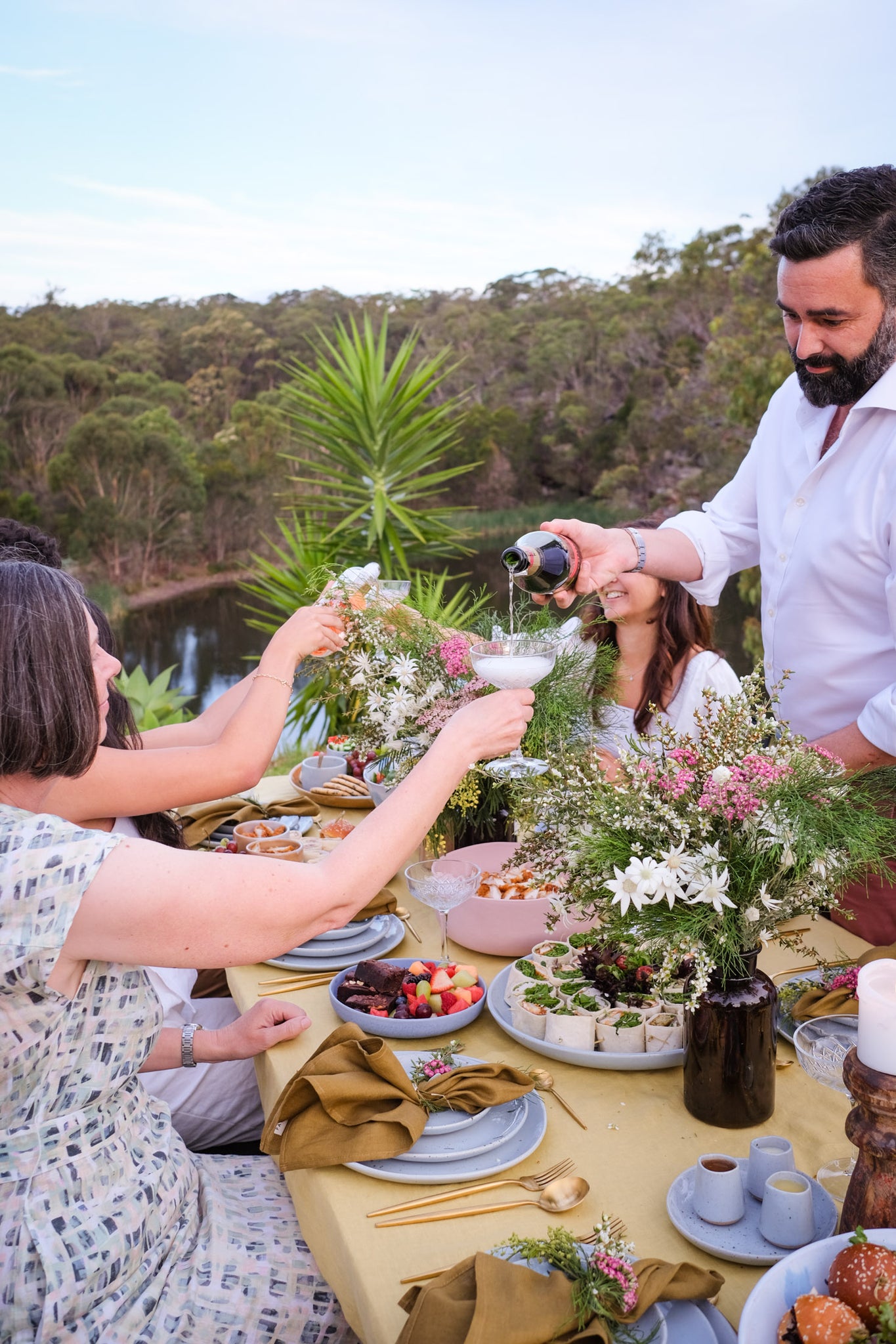 Man pouring Mumm Champagne at a summer outdoor dining event by Palinopsia Ceramics
