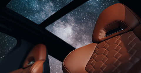 brown leather car seats in a car with an open sun roof showing the stars at night