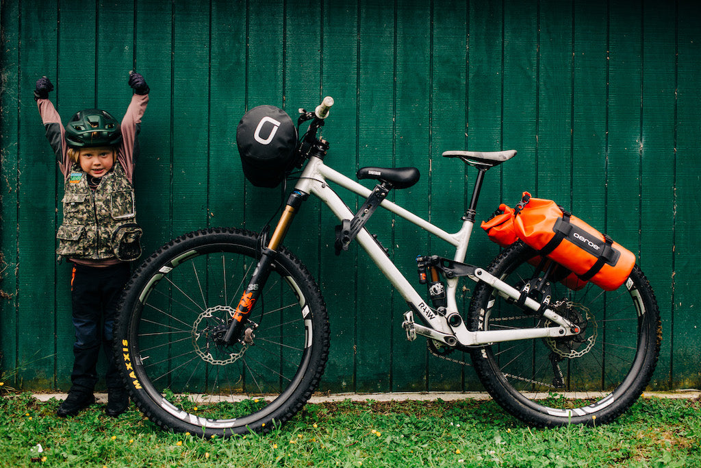 Kid and mountain bike standing in front of green wall