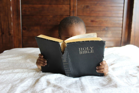 Small child reading an older Bible