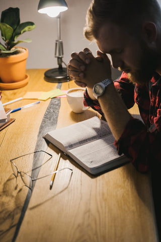 Man praying over a Bible