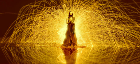 Woman praying with yellow firecrackers going off in the background