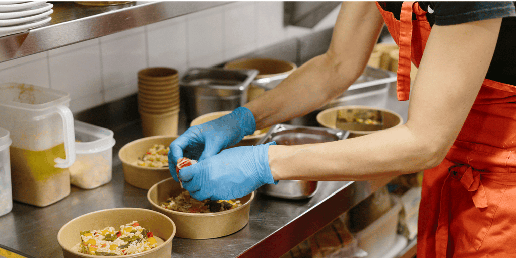 A person preparing meals using biodegradable gloves.
