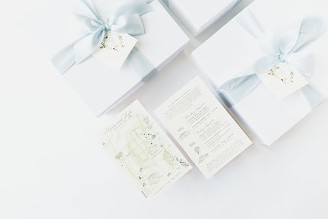 white boxes with blue ribbons and water color map and itinerary