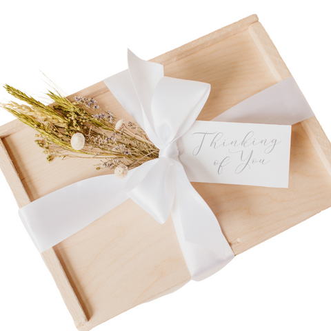 closed wooden box with white ribbon, thinking of you tag, dried florals