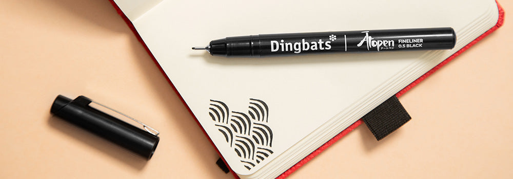 A Dingbats pen placed on a notebook