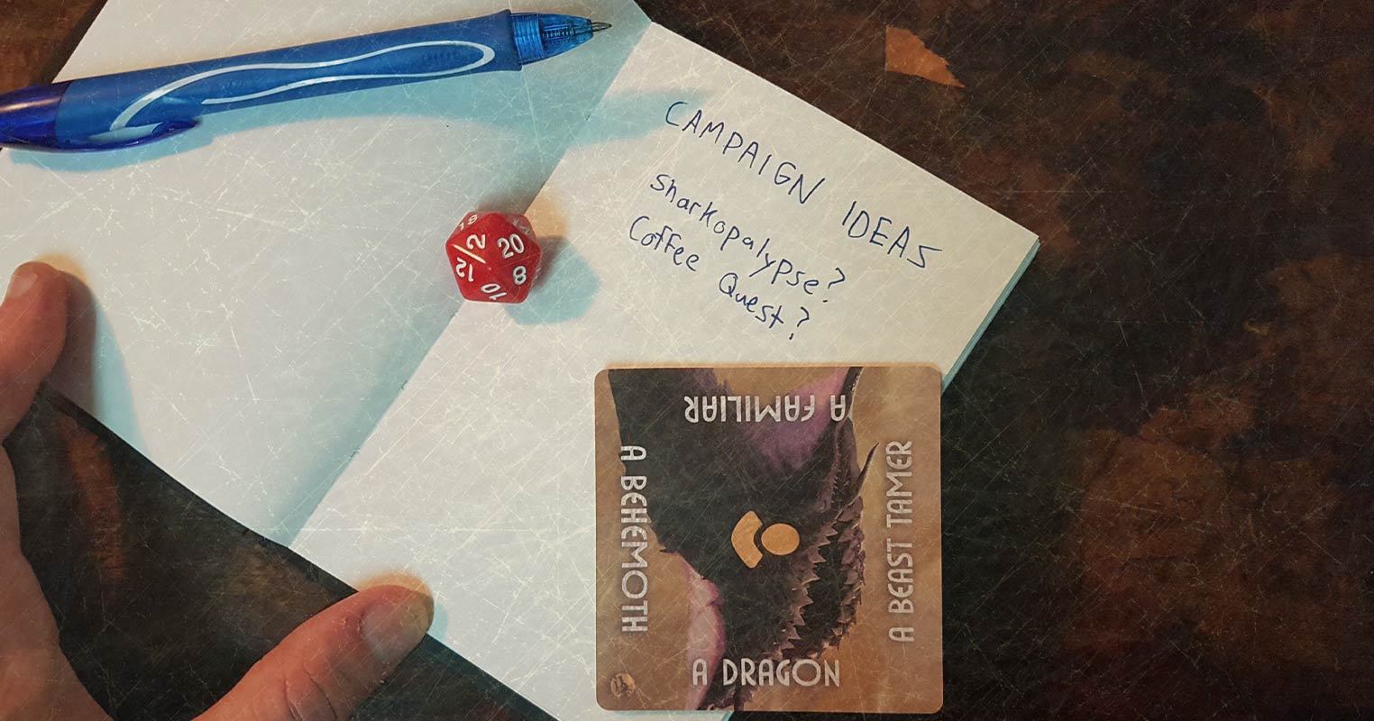 Photo of a d20, D&D notebook, and card from The Story Engine Deck of prompts