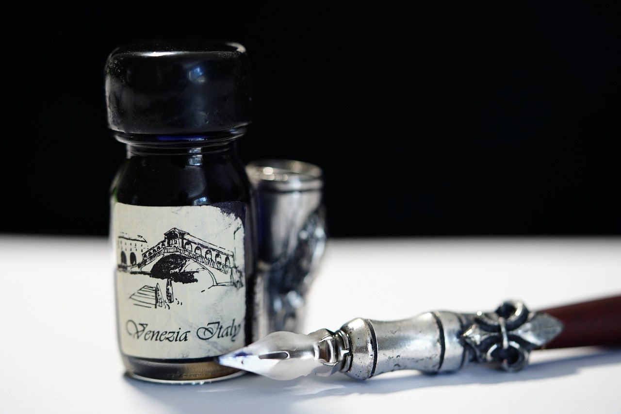 An old-fashioned pen next to a bottle of ink.