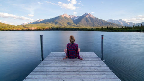 woman on a dock beside a calm lake