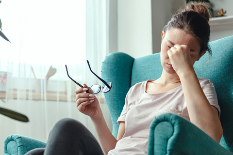 woman sitting on chair with hand on head due to headache