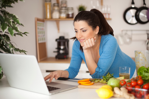 woman making dinner and following recipe on computer