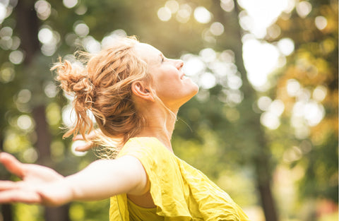 woman standing in sunshine with arms spread wide